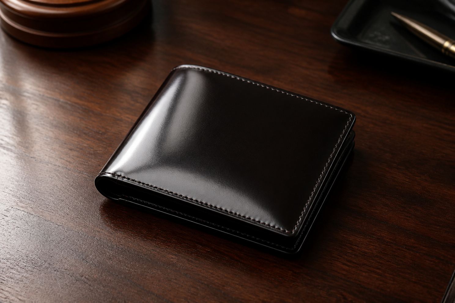 黒いコードバンの二つ折り財布を木の机に置いて斜め上から見たところ